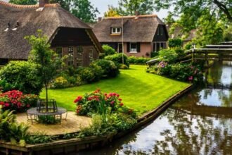 Scenic canal in Giethoorn village featuring traditional thatched roof houses and wooden footbridges in summer