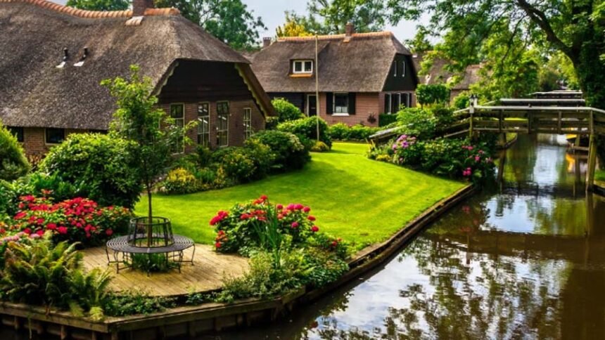 Scenic canal in Giethoorn village featuring traditional thatched roof houses and wooden footbridges in summer