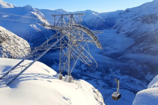 The Loen Skylift cable car ascending a steep mountain cliff overlooking the blue Nordfjord in Norway