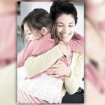 A loving parent hugs a young child before bedtime in a cozy bedroom environment, with dim lighting and no screens.