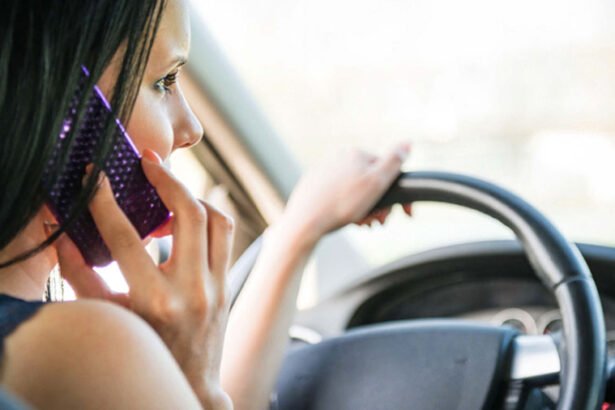 Close-up of a driver holding a smartphone while steering, illustrating the dangers of distracted driving