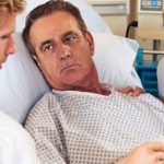 A doctor and a patient's wife engaging in a focused and respectful discussion at his bedside in a hospital